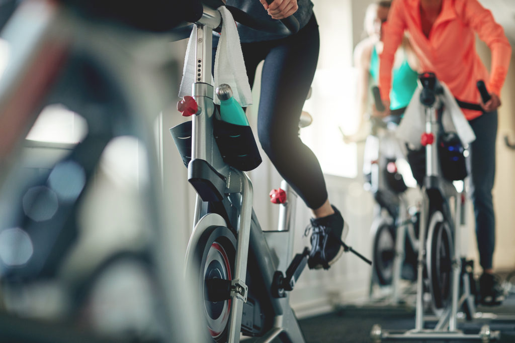 Cropped shot of women working out with exercise bikes in a spinning class at the gym